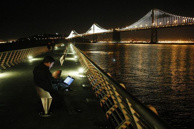 Leo Villareal works from his computer on Pier 14 to sequence lights on the Bay Bridge on Sunday. Photo: James Tensuan-image via The Chronicle 